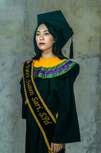 Portrait of woman standing against wall