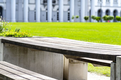 Benches and tables with flowers arranged in a row in the park, in the background a large building.