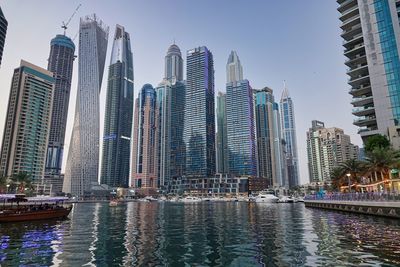 Boats in river in city against sky