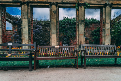 Empty bench in park against building