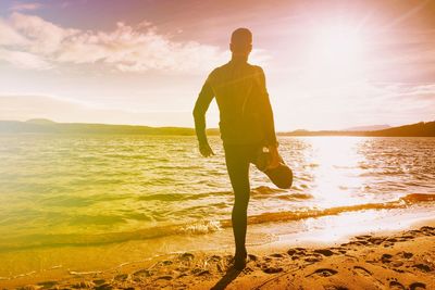 Runner stretching knee and leg. man exercises at lake. abstract lighting, colorful flare.