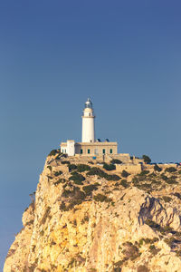 Low angle view of lighthouse against buildings against clear sky