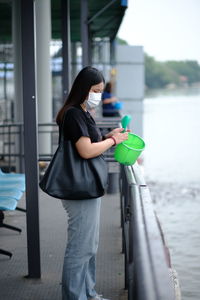 Side view of woman standing against the water