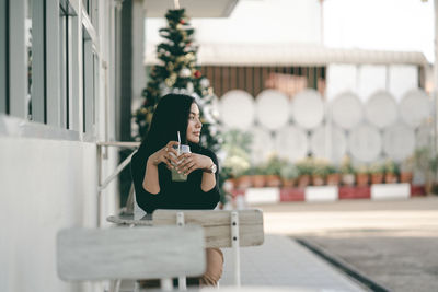 Smiling woman with drink sitting at outdoor cafe