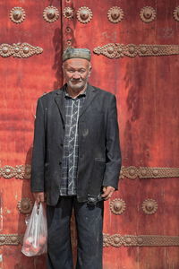 Full length portrait of a man standing against wall