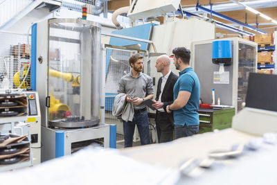 Businessman and employees discussing in modern factory