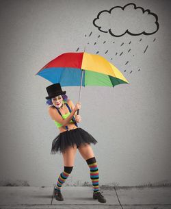 Woman with umbrella standing against wall