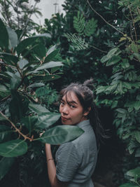 Portrait of beautiful young woman standing by plants