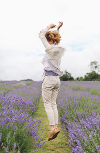 Full length of woman jumping on lavender field