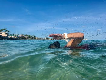 Man swimming in sea against sky