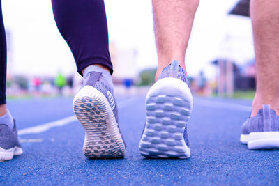 Low section of couples wearing sports shoes on running track