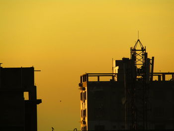 Silhouette of construction site against sky during sunset