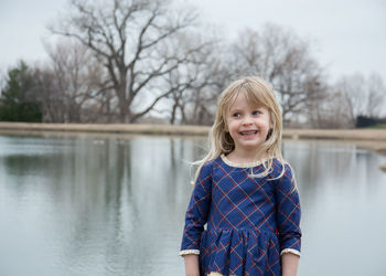 Portrait of smiling girl standing against lake
