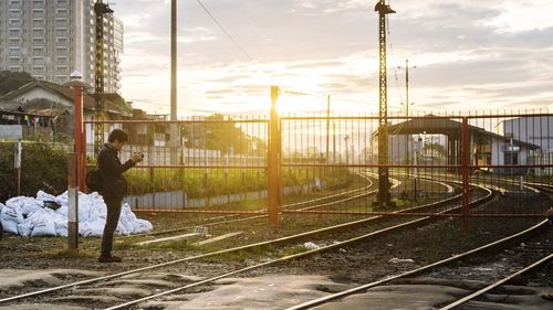 Railroad tracks in city against sky during sunset