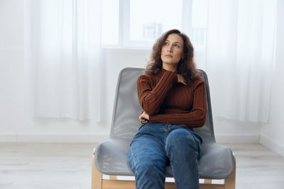 Young woman sitting on chair at home