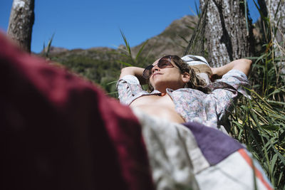 Woman with sunglasses have a bathsun on hammock during a trip.