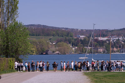 Group of people by the sea against clear sky