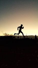 Silhouette man running on field against sky during sunset