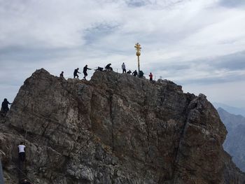 People on rock formation against sky