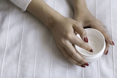 Beautiful groomed woman's hands with cream jar on the blanket. moisturizing cream, soft skin. health