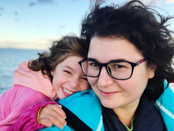 Portrait of smiling mother and daughter against sea