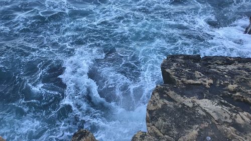 High angle view of waves breaking on rocks