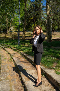 Portrait of young woman standing against trees