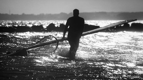 Rear view of silhouette man standing by sea