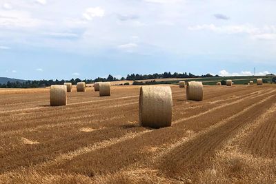 Hay bales on field against sky