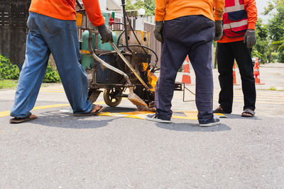 Group of road worker paint traffic lines on asphalt road surface.