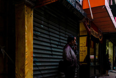 Side view of man standing against building