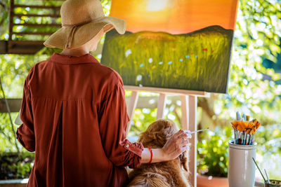 Young female artist working on her art canvas painting outdoors in her garden. creativity concept.