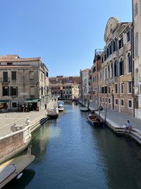 Canal amidst buildings in city against clear sky