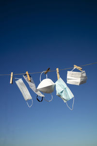 Low angle view of flags hanging against clear blue sky