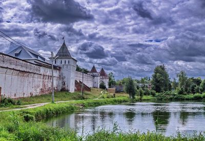 Buildings by lake against sky