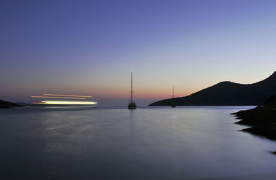 Silhouette sailboats in sea against clear sky at sunset