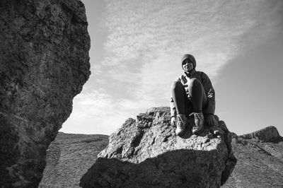 Low angle view of woman sitting on rock