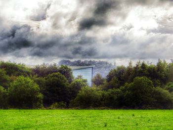 Scenic view of grassy field against cloudy sky