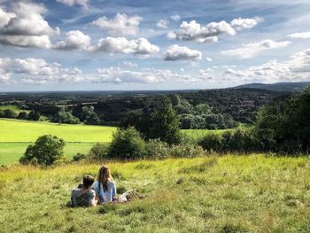 People sitting on field against sky