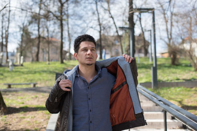 Young man standing against trees