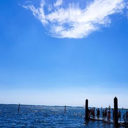 People on sea against blue sky