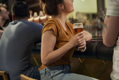 Midsection of woman holding beer glass at bar