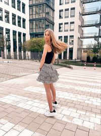 Portrait of a young woman standing against building in city