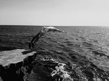 Man swimming in sea against clear sky