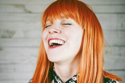 Redhead woman laughing against wall