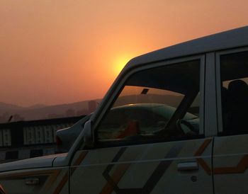 Close-up of car against sky during sunset