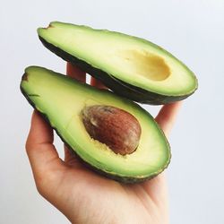 Cropped image of hand holding fruit over white background