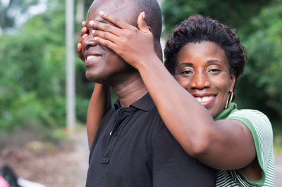 Happy young woman in love hides the eyes of her fiance with his hands