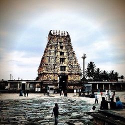 People walking in city against cloudy sky