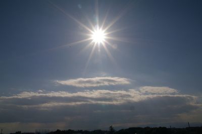 Low angle view of sun shining through clouds